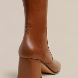 K&ouml;nnte beinhalten: Braune Lederstiefel mit Blockabsatz. Die Stiefel haben eine spitze Zehenpartie und einen Rei&szlig;verschluss an der R&uuml;ckseite.