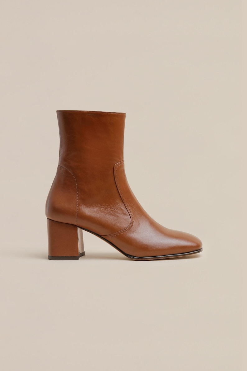 K&ouml;nnte beinhalten: Braune Lederstiefel mit Blockabsatz. Die Stiefel haben eine spitze Zehenpartie und eine leicht abgerundete Form.