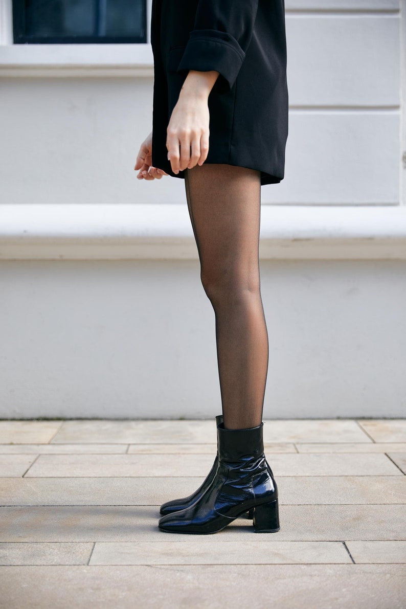 May include: Black ankle boots with a block heel and a pointed toe. The boots are made of patent leather and have a sleek, modern design.