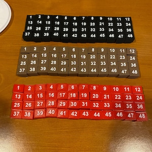 May include: Three sets of number tiles, each set with numbers 1 through 48. The first set is black, the second is brown, and the third is red.