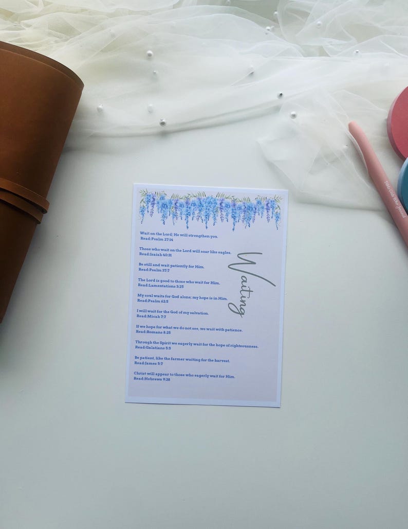 Peut inclure: Une carte blanche avec le mot "Waiting" en &eacute;criture cursive et un motif floral bleu. La carte contient un texte inspirant de la Bible. La carte est sur une surface blanche avec un fond en tissu transparent.