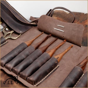 May include: A brown leather case with multiple wooden crochet hooks. The hooks are labeled with sizes 1.50, 1.75, 2.00, 2.25, 2.50, and 3.00.