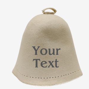 Könnte beinhalten: Ein beiger Filzhut mit einer spitzen Spitze und einer dekorativen Schnur. Der Hut hat einen gewellten Rand und ein Punktmuster um den Rand. Der Text "Your Text" ist auf der Vorderseite des Hutes gestickt.