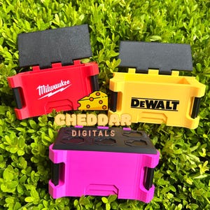 May include: Three small toolboxes, one red with the Milwaukee logo, one yellow with the DeWalt logo, and one pink with black accents and a textured top.