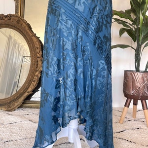 May include: A blue maxi dress with a floral pattern. The dress has a flowing skirt and a fitted bodice. The dress is made of a soft, lightweight fabric.