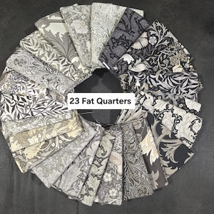 Pode incluir: Uma coleção de 23 fat quarters dispostos em círculo. Os tecidos apresentam vários desenhos florais e botânicos em tons de cinza, preto e creme. O texto "23 Fat Quarters" é visível.