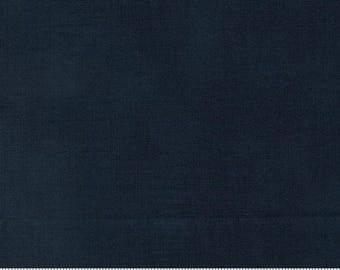 May include: A solid dark navy blue fabric with a visible woven texture. A white ruler is positioned along the bottom edge, showing measurements in centimetres from 0 to 18, with the text moda and www.modafabrics.com printed on the ruler.