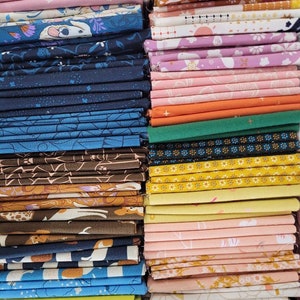 Peut inclure: Un empilement de tissus colorés avec divers motifs. Les tissus présentent des motifs floraux, animaliers et géométriques dans des tons de rose, bleu, marron et jaune. L'image présente une variété de textures et de styles, adaptés à divers projets de couture.