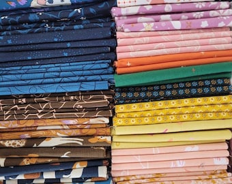 May include: A large collection of folded fabric squares stacked in two columns. The fabrics feature various patterns including floral, geometric, and animal prints in a diverse color palette of pink, blue, brown, yellow, orange, green, and white.
