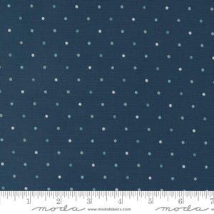 May include: A dark blue fabric featuring a repeating pattern of small, evenly spaced white and light blue polka dots. A white ruler is visible at the bottom edge, showing a measurement scale of 7 inches across the width of the textile.