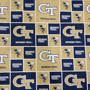 May include: A fabric pattern featuring a repeating grid of navy blue and gold squares. The design includes the Georgia Tech GT logo, the text Georgia Tech, and a graphic illustration of a yellow and black hornet mascot throughout the print.