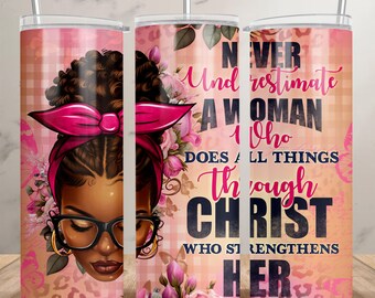 May include: A pink and white tumbler with a floral design and a black woman with glasses and a pink headband. The tumbler has the text "Never underestimate a woman who does all things through Christ who strengthens her".