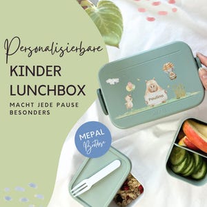Könnte beinhalten: Eine türkisgrüne Kinder-Lunchbox mit einem Cartoon-Nilpferd- und Enten-Design, personalisiert mit dem Namen "Paulina". Die Lunchbox ist geöffnet und zeigt geschnittene Äpfel und Gurken. Der Text auf der Lunchbox lautet "Kinder Lunchbox".