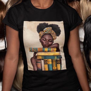 May include: Black t-shirt featuring a graphic of a woman with a head wrap resting on a stack of books. The graphic has a vintage look with muted colors. The woman's skin is dark, and the books are yellow and blue.