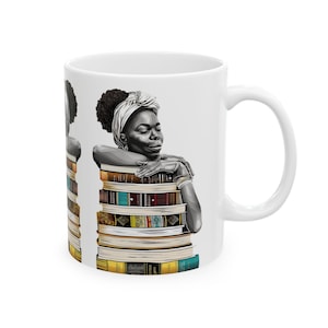 May include: White ceramic mug featuring a black and white illustration of a person leaning on a stack of books. The person is wearing a head wrap and jewelry. The books have colorful spines.