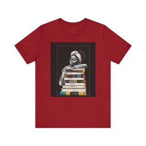 Afrocentric graphic tee shirt featuring a peaceful Black woman embracing a stack of books, symbolizing education, knowledge, freedom, and generational legacy.