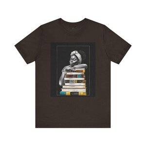 Afrocentric graphic tee shirt featuring a peaceful Black woman embracing a stack of books, symbolizing education, knowledge, freedom, and generational legacy.