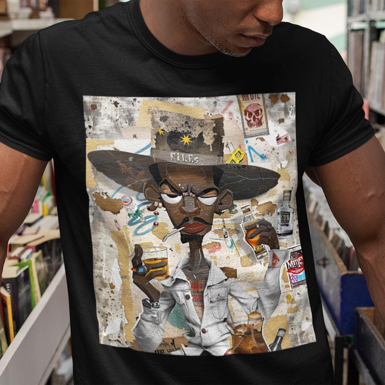 Black Cowboy Tee featuring a cartoon-style African American cowboy smoking a cigarette and drinking whiskey. A bold, graffiti collage pop art design with an edgy Western and Afrocentric cultural vibe.