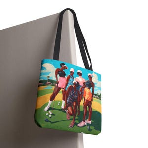 May include: A tote bag featuring a colorful painting of five women playing golf on a green course. The women are wearing colorful clothing and hats. The bag has black straps.