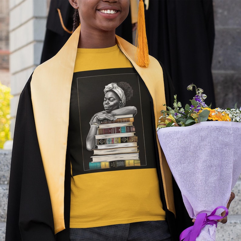 Afrocentric graphic tee shirt featuring a peaceful Black woman embracing a stack of books, symbolizing education, knowledge, freedom, and generational legacy.