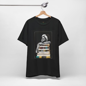 Afrocentric graphic tee shirt featuring a peaceful Black woman embracing a stack of books, symbolizing education, knowledge, freedom, and generational legacy.