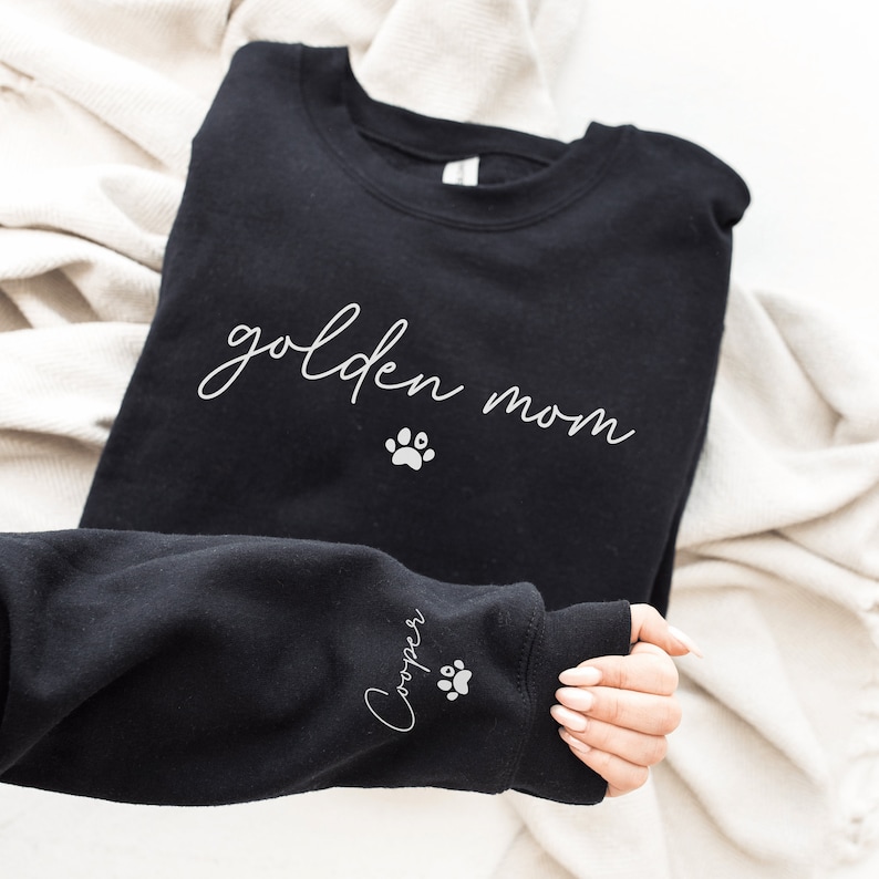 May include: Black sweatshirt with the text "golden mom" and a paw print on the front. The sleeve has the text "Cooper" and a paw print.