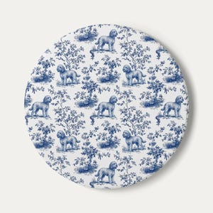 May include: A round, white decorative item with a blue toile pattern featuring dogs and floral elements. The design is repeated across the surface, creating a classic and elegant aesthetic. The item is circular in shape.