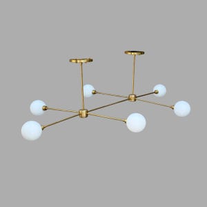 Op de afbeelding: Moderne messingkleurige kroonluchter met zes witte bolvormige lampen. De armatuur heeft een lineair ontwerp met meerdere armen die uitgaan van een centraal punt. De lamp is aan het plafond bevestigd.