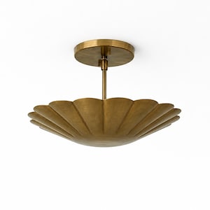 May include: A brass-colored ceiling light fixture with a scalloped, shell-like shade. The fixture has a round base and a central rod connecting to the shade. The design is elegant and decorative, suitable for interior lighting.