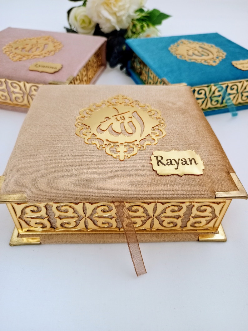 May include: A gold velvet box with a gold Arabic calligraphy design and a gold nameplate that says "Rayan". The box has a gold ribbon.