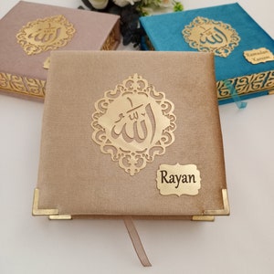 May include: Three decorative boxes with gold Arabic calligraphy and a gold inscription that reads "Rayan". The boxes are covered in fabric and have gold accents. The boxes are on a white surface.
