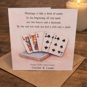 May include: A greetings card featuring a deck of cards illustration. The card reads, "Marriage is like a deck of cards. Happy Ruby Anniversary Darren & Linda." The card is on a brown envelope, with a lit candle in the background.