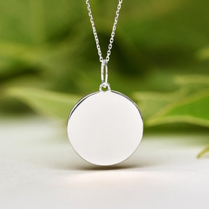 May include: A silver necklace with a round pendant. The pendant is smooth and has a shiny finish.