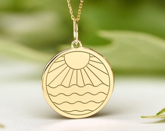 May include: A gold necklace with a round pendant featuring a sun and waves design.