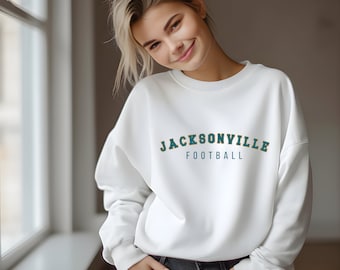 May include: White sweatshirt with a green and yellow Jacksonville Football logo.