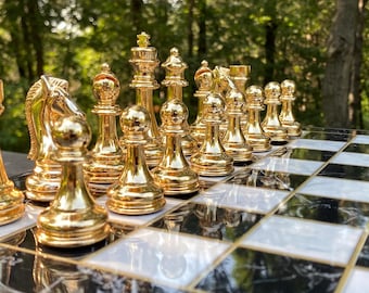Juego de ajedrez personalizado: piezas doradas, negras y plateadas, tablero con diseño de mármol.