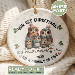 May include: A round ceramic Christmas ornament featuring a family of five owls wearing winter hats and scarves. The text reads "Our 1st Christmas as a Family of Five" with the year 2025. The ornament has a gold string for hanging.