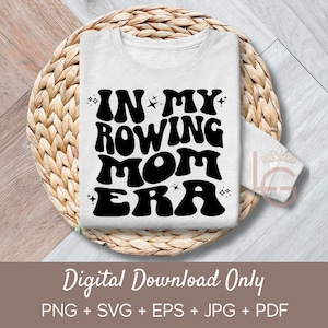 Puede incluir: Una camiseta blanca de manga larga con el texto negro "IN MY ROWING MOM ERA" en una tipografía retro. La camiseta se muestra sobre un salvamanteles redondo y tejido. Las palabras "Digital Download Only" están en la parte inferior.
