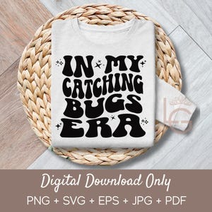 May include: A white t-shirt with black text that reads "In My Catching Bugs Era" in a retro font. The text is surrounded by small stars.