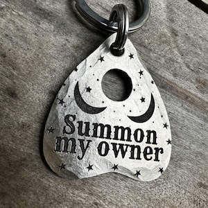 以下が含まれることがあります： 三日月と星がデザインされた、魔女のボードの形をした銀色のキーホルダー。キーホルダーには「Summon my owner」という文字が刻まれています。