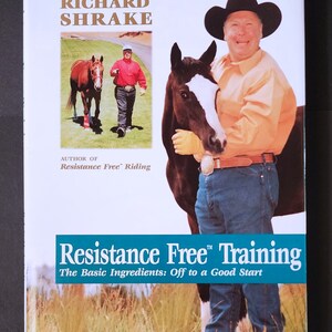 May include: Book cover with a blue and white title "Resistance Free Training" and the subtitle "The Basic Ingredients: Off to a Good Start". The cover features a man in a cowboy hat and a brown and white horse.