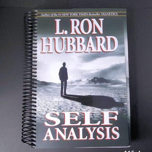 May include: A spiral-bound book titled "SELF ANALYSIS" by L. Ron Hubbard. The cover features a silhouette of a person standing on a cracked earth landscape under a cloudy sky. The text "Author of the #1 NEW YORK TIMES Bestseller DIANETICS" is at the top.