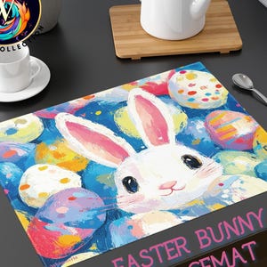 May include: Easter bunny placemat featuring a white bunny with pink ears and a smiling face, surrounded by colorful Easter eggs on a blue background. The placemat has the text "Easter Bunny Placemat" in pink.