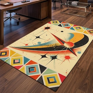 May include: A rectangular area rug featuring a cream-colored background with a central graphic design of a stylized orange crescent moon, a red sun, and black starburst shapes. The border displays a repeating pattern of colorful geometric diamonds.