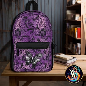 May include: A purple backpack with a black butterfly design on the front pocket. The backpack features a floral pattern in shades of purple and black. It has a black zipper pocket and a black handle. The Whimsteria Collection logo is in the bottom right corner.