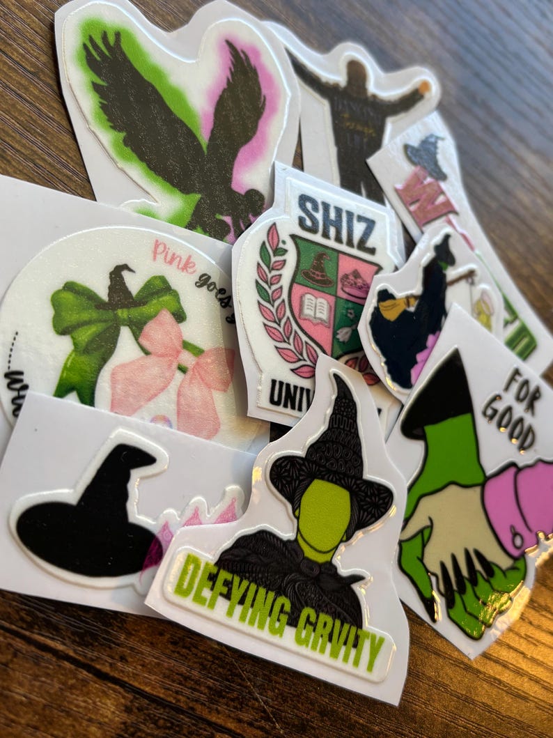Może przedstawiać: Kolekcja naklejek z r&oacute;żnymi wzorami i tekstem. Wzory obejmują sylwetkę osoby, orła, czarownicy oraz tekst, kt&oacute;ry brzmi "SHIZ", "Pink goes" i "Defying Gravity".