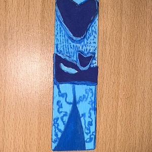 Peut inclure: Marque-page en bois bleu avec un motif de cœur bleu foncé et un design stylisé. Le marque-page est peint dans des tons de bleu et comporte un petit trou en haut pour une attache. Mesure environ 15 cm de long.