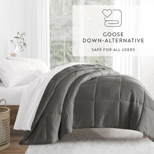 May include: A gray goose down alternative comforter on a bed with white sheets. The comforter is made of a soft, breathable fabric and is perfect for year-round use. Goose Down Alternative - Safe for all users.