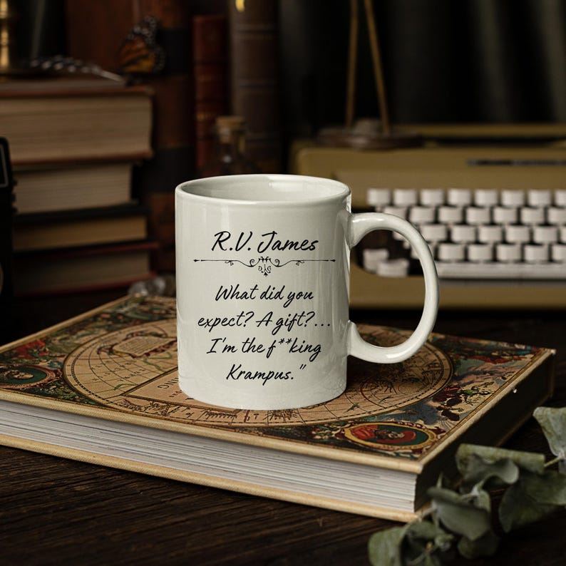 Puede incluir: Una taza de cer&aacute;mica blanca con texto impreso en negro que dice: R.V. James. What did you expect? A gift?... I'm the f**king Krampus. La taza tiene un asa est&aacute;ndar y un cuerpo cil&iacute;ndrico liso con un acabado brillante y letras claras y legibles.