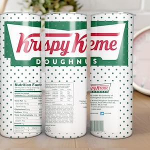 May include: A white tumbler with a green and red Krispy Kreme Doughnuts logo. The tumbler has a white background with green polka dots. The back of the tumbler has nutrition facts and contact information for Krispy Kreme.